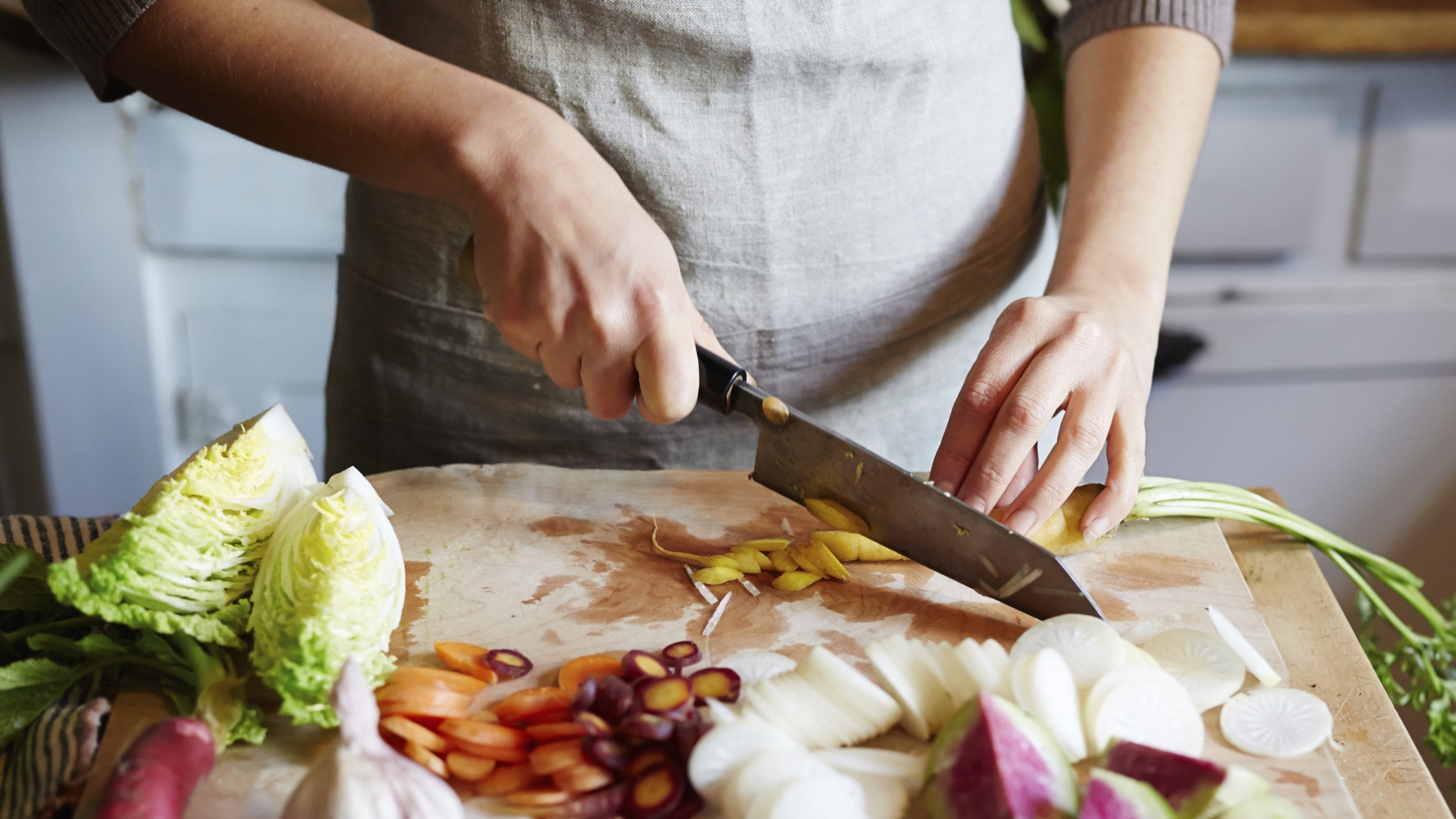 Woman cooking in kitchen with ingredients around her