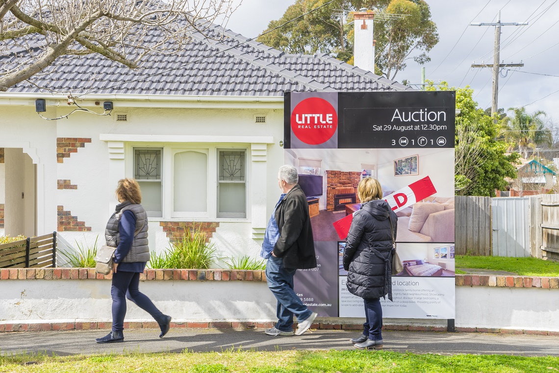 people walking past a house after auction